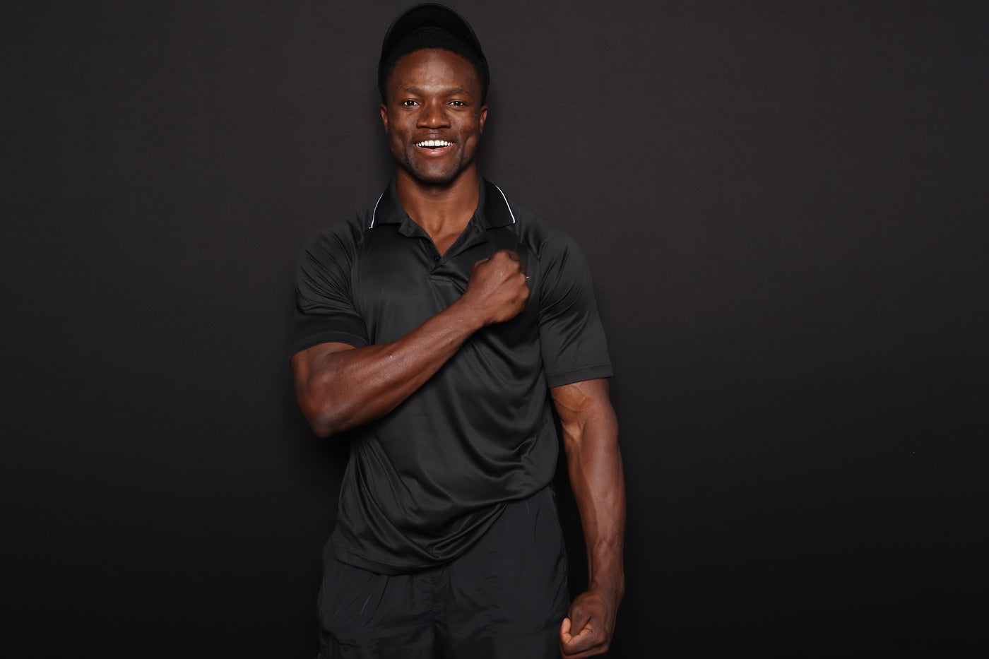 Man wearing a black polo shirt against a dark background